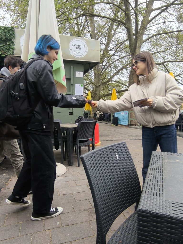 la ragazza di destra distribuisce un volantino alla ragazza di sinistra